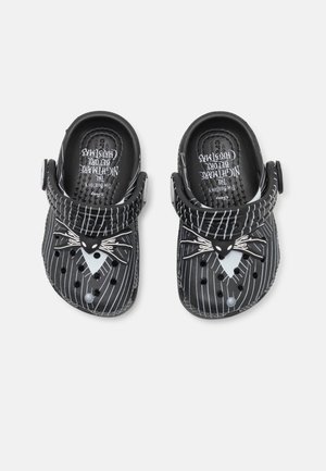 Sorte træsko med hvide nålestriber og et Jack Skellington-ansigtsdesign, der har justerbare hælremme og ventilationshuller.