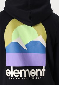 Musta huppari, jossa on graafinen suunnittelu vuorista ja auringosta vihreällä, keltaisella, sinisellä ja violetilla, ja "elementti"-teksti alareunassa.