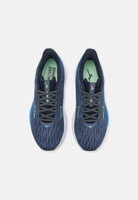 Μπλε και ναυτικές αθλητικές παπούτσια με υφασμάτινο άνω μέρος με υφή, πράσινες λεπτομέρειες και μαλακή λευκή σόλα. Τα κορδόνια είναι σκούρο γκρι με ανακλαστικά στοιχεία.