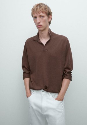 Brown, long-sleeve polo shirt with a relaxed fit and collar, paired with white, straight-leg jeans. Minimalist design and soft texture.