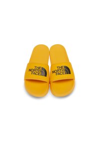 Žluté skluzavkové sandály vyrobené z gumy s širokým černým popruhem s logem, který obsahuje nápis "THE NORTH FACE" a zakřivený design loga.