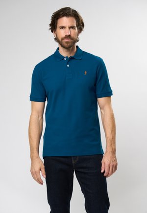 Teal polo shirt van katoenmix, met een kraag, een knoopsluiting met twee knopen en een klein logo. Gekocht met donkere jeans. Soepele textuur.