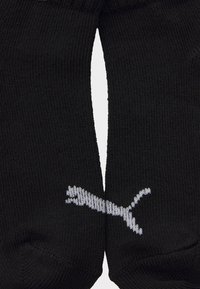 Calcetines de algodón negros con textura acanalada, que presentan un logo blanco exhibido de manera destacada en un lado. El diseño es clásico y sencillo.