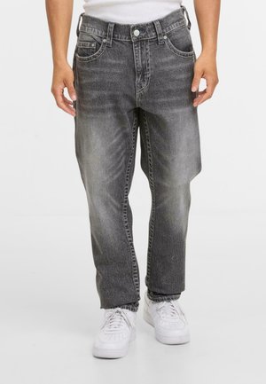 Black denim jeans with a faded wash, five-pocket design, belt loops, and a straight fit. Paired with white sneakers.