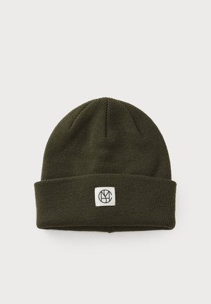 Oliven grønn strikket lue med brettet mansjett og en firkantet hvit lapp med en svart logo. Teksturert, mykt materiale, avrundet topp.
