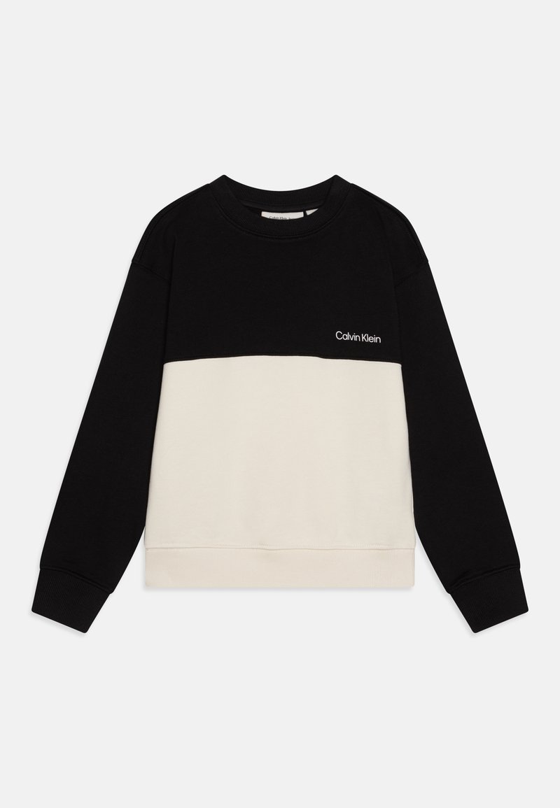 Długi sweter z długim rękawem w kolorach czarnym i beżowym, z logo Calvin Klein na czarnej górnej części klatki piersiowej.