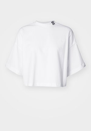 White cropped t-shirt made of cotton, featuring wide short sleeves and a high neckline. The label "HUGO" is printed in black on the collar.