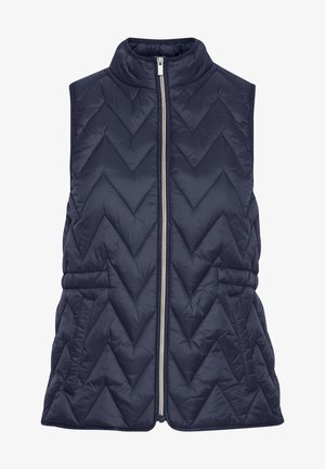 Tamsiai mėlyna be rankovių pūkinė liemenė su zigzaginiu siuvinėjimu, aukštu apykakle ir užtrauktuku priekyje. Yra surinkta liemens linija, kuri suteikia formą.