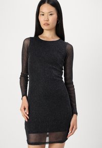 Μαύρο γυαλιστερό φόρεμα με μακριά διάφανα μανίκια, εφαρμοστή σιλουέτα, στρογγυλή λαιμόκοψη και διαφανές τελείωμα. Λείο υλικό με λαμπερή λεπτομέρεια.