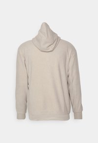 Beige hoodie met een trekkoord in de capuchon, lange mouwen en geribde manchetten. Zachte textuur, eenvoudig ontwerp en geen zichtbare logo's of patronen.