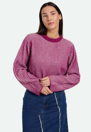 Fuchsiový a biely pruhovaný pletený sveter s rebrovanou textúrou, okrúhlym golierom a dlhými rukávmi, skombinovaný s džínsovou sukňou s roztrhnutým švom.