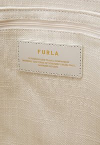 Beige textiel interieur met een goudgeëtste Furla-label. Soepele ritssluiting en minimalistisch ontwerp.
