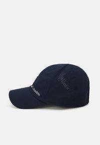 Granatowa czapka z wygięrim daszkiem, wykonana z przewiewnego materiału. Posiada perforowany wzór po bokach i biały logo z przodu.