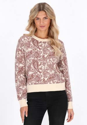 Hellbeige Pullover mit burgunderfarbenem Paisleymuster. Gerippter Rundhalsausschnitt und Bündchen, cropped Design. Kombiniert mit schwarzen Hosen.