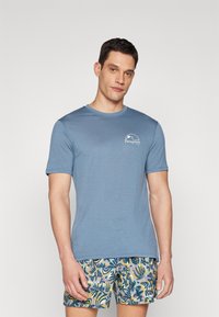 Blue, short-sleeve t-shirt with a round neckline and subtle texture. Features a white Patagonia logo on the left chest.