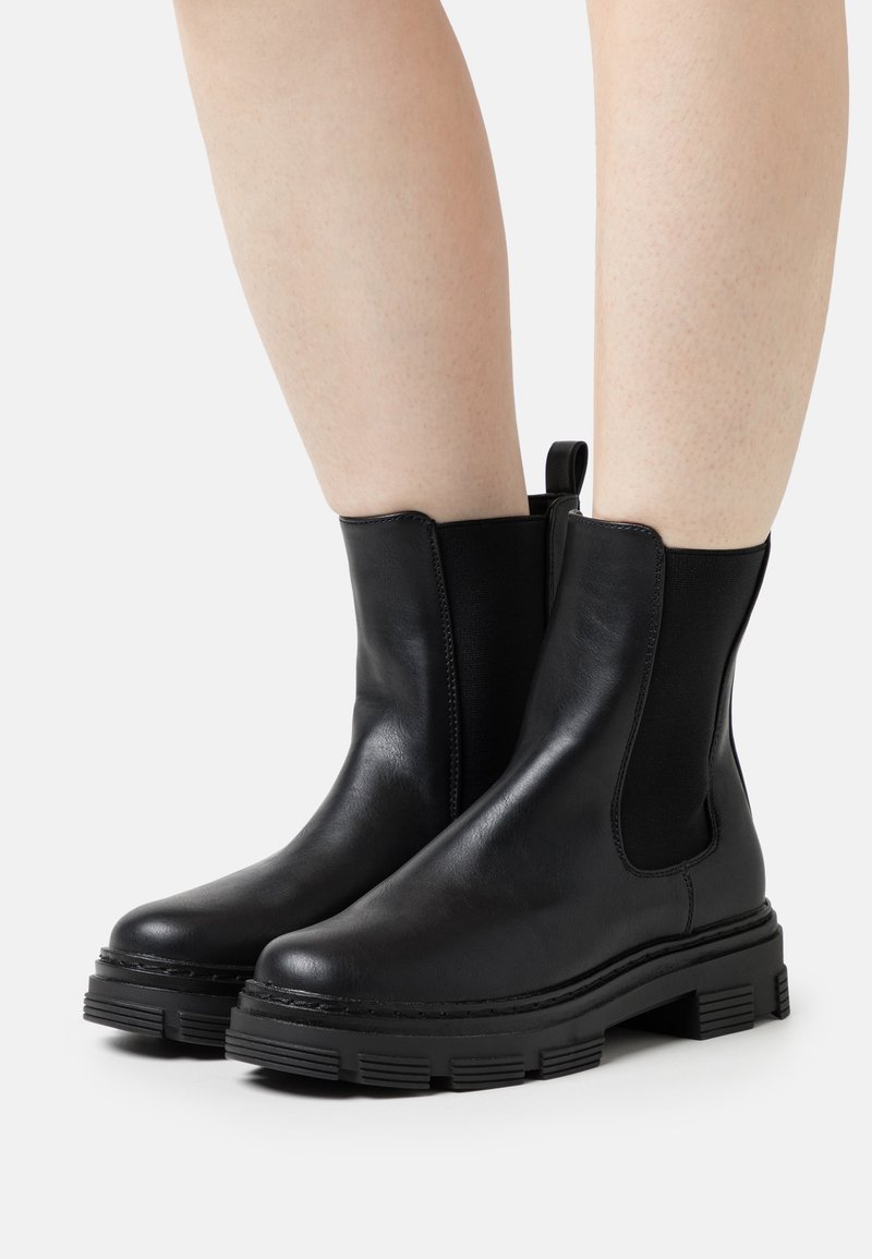 Black leather ankle boots with elastic side panels, rounded toes, and textured rubber soles featuring a lug design for traction.