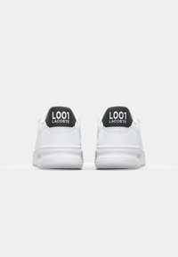 Hvite sneakers med glatt lærøvre, polstret tunge og hæl. Svarte detaljer på hælen med teksten "L001 LACOSTE". Gummisåle med riller.
