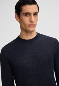 Navyblauer Langarmpullover aus einem strukturierten, leichten Strick. Verfügt über einen Rundhalsausschnitt und eine leicht taillierte Silhouette.