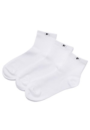 Trzy pary białych skarpetek do kostek z prążkowanymi ściągaczami i małą czarną etykietą z literą "F" na każdym ściągaczu, ułożone obok siebie.