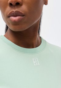 Κοντινό πλάνο ενός ατόμου που φοράει μια ριμπ πουκάμισο σε μέντα με μικρό λευκό λογότυπο Nike στο στήθος, εμφανίζοντας τα χείλη, το πηγούνι και τον λαιμό.