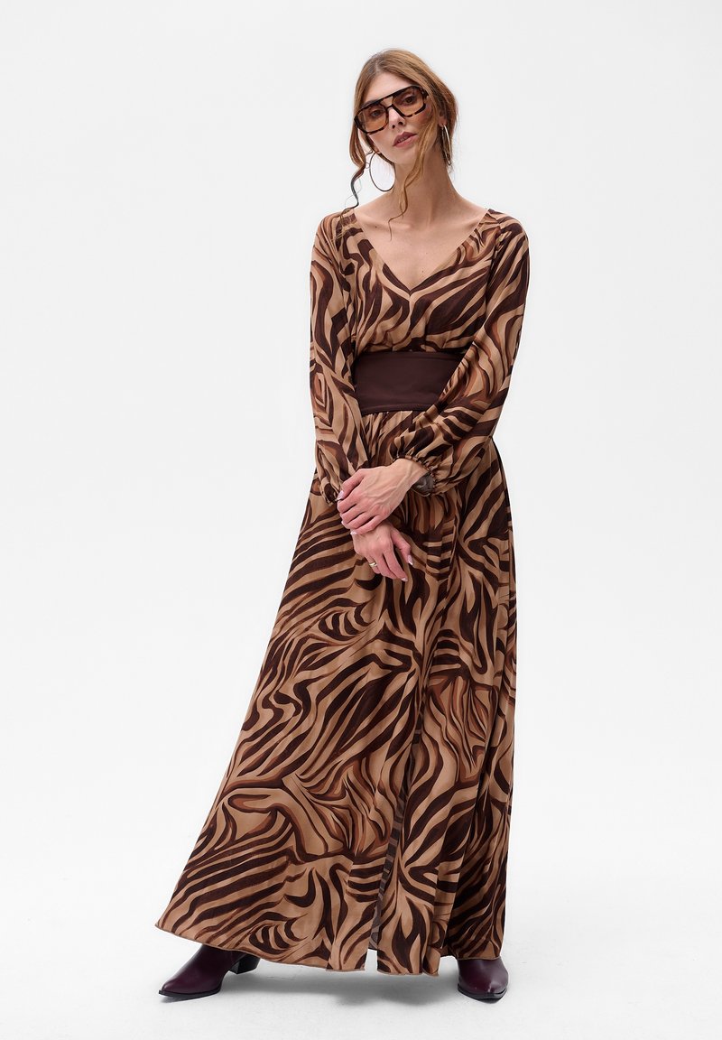 Maxi sukienka z przezroczystego brązowego materiału z wirującym wzorem zebry. Dekolt w kształcie litery V, długie rękawy i dopasowany brązowy pas w talii.