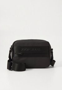 Juoda stačiakampio formos rankinė per petį su reguliuojamu dirželiu, priekyje su užtrauktuko kišene ir įspaustu užrašu „JOOP! JEANS“ ant priekinio skydelio.