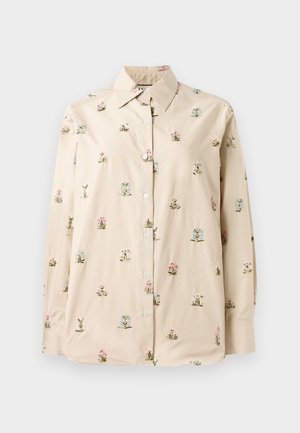 Camisa de botones crema con bordado floral en rosa y azul. Tejido suave y liso, con cuello clásico y mangas largas.