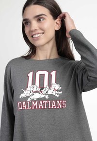 Camiseta de manga larga gris con un gráfico de cachorros dálmatas corriendo y "101 DALMATIANS" en texto blanco y rojo. Textura de tela suave.