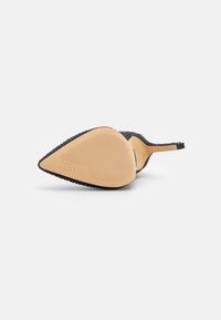 Scarpa nera con tacco alto, punta affusolata, upper con texture e suola in gomma beige con scanalature orizzontali; design e struttura minimalista.
