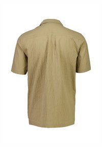 Camisa de manga corta en beige claro, con un tejido texturizado, cuello con solapa y un pliegue en la parte posterior para mayor comodidad al moverse.