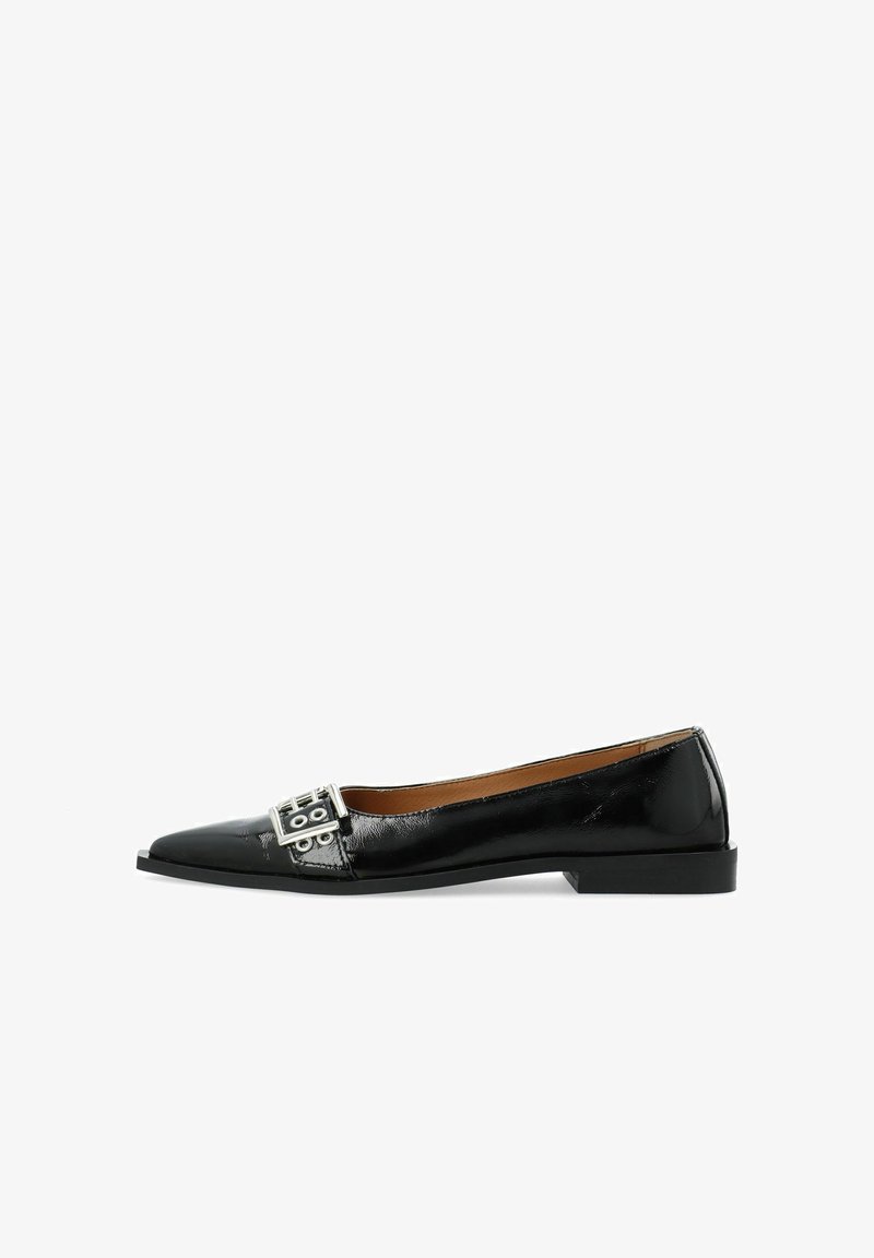 Zapato plano de charol negro con punta afilada, que presenta un acento de hebilla plateada en el empeine y una suela plana minimalista.