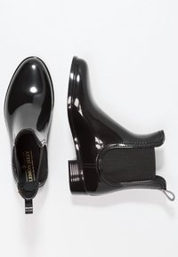 Bottines en cuir verni noir avec des panneaux latéraux élastiques et une languette. Fini lisse avec un bout arrondi et un petit talon empilé.