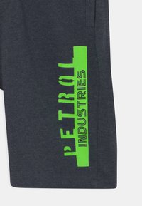Tmavě šedé šortky vyrobené z bavlněné směsi s velkým zeleným grafickým potiskem "PETROL INDUSTRIES" na boku, se strukturovaným povrchem.