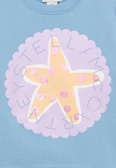 Kollane tähtkalmaar roosade täppidega lilla sisselõigatud ringi sees helesinisel kangal, millel on tekst "STELLA MCCARTNEY."