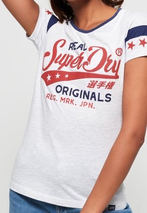 Hvid bomulds t-shirt med korte ærmer, blå og røde detaljer, med et fremtrædende grafisk tekstdesign og stjerner på skuldrene.