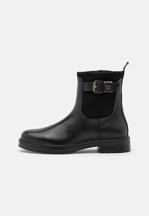 Stivali neri alla caviglia realizzati in pelle e suede, con zip laterale, dettagli con una fibbia dorada e una suola in gomma testurizzata.