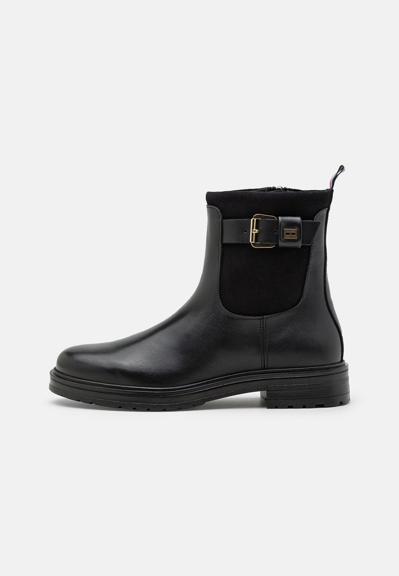 Stivali neri alla caviglia realizzati in pelle e suede, con zip laterale, dettagli con una fibbia dorada e una suola in gomma testurizzata.