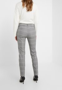 Grå rutiga byxor med skräddarsydd passform, som har en mjuk textur, bakfickor och subtila randningar. Bärs med en ljus tröja och klackar.