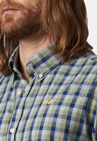 Camisa de cuadros para hombre en verde, azul y gris. Cuenta con un cuello abotonado, logo bordado en dorado y botones blancos. Material de algodón.