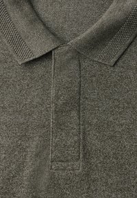 Polo-shirt vert foncé en tissu texturé, présentant un col classique et une patte de boutonnage à trois boutons. Motif chiné subtil présent.