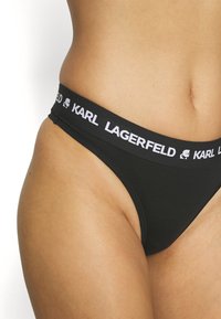 Svart bikiniunderdel med ett brett midjeband med "KARL LAGERFELD" i vit text. Tillverkad av mjukt, slätt tyg med en klassisk passform.
