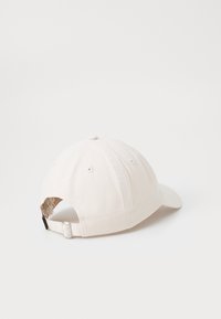 Căciulă de baseball bej cu vizor curbat, curea ajustabilă și design cu șase panouri. Fabricată din bumbac, cu găuri de ventilație cusute.