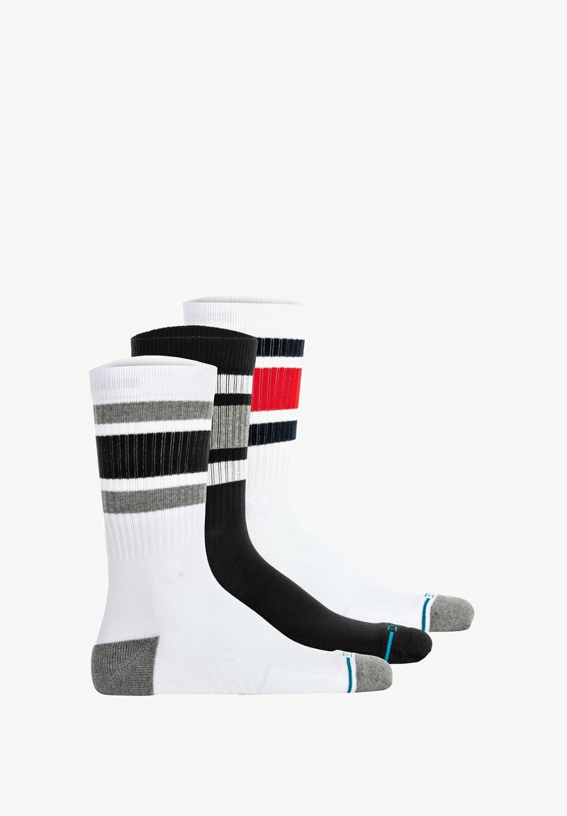 Tre par sokker: et par hvid med sorte og røde striber, et gråt med sorte striber og et sort ensfarvet par. Alle med ribbet tekstur.