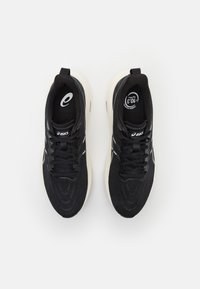 Black athletic shoes with textured fabric upper, white rubber sole, and laces. Features logo on tongue and side. Clean, streamlined design.
