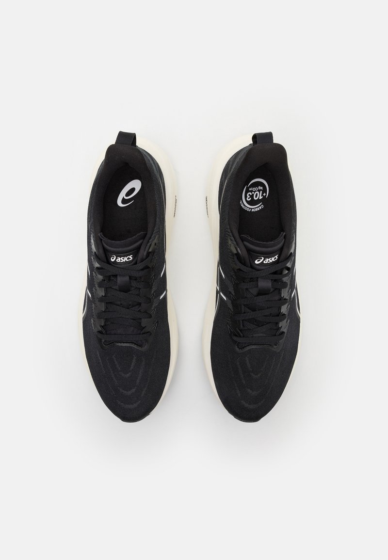 Zapatillas deportivas negras con parte superior de tela texturizada, suela de goma blanca y cordones. Presenta el logotipo en la lengüeta y el costado. Diseño limpio y aerodinámico.