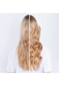 Cheveux blonds longs, divisés en deux sections : le côté gauche est lisse et ondulé, tandis que le côté droit est plus structuré avec des vagues bien définies. Fond clair.