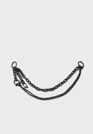 Chaîne noire et corde rayée noir et blanc liées par des anneaux métalliques sur un fond clair.