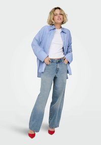 Zila svītrota pārmēra krekls, pieguļošs balts tops, gaiši zili plati džinsi un sarkani norādīti zābaki. Vienkārša dizaina ar kontrastējošām krāsām un materiāliem.