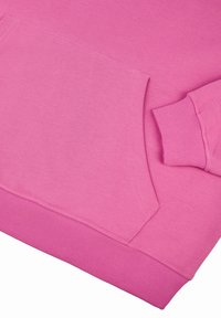 Felpa rosa con tasca a marsupio, polsini e orlo a coste. Texture liscia con dettagli di cucitura fine e senza loghi visibili.