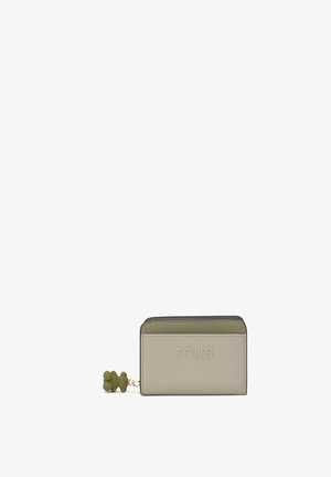 Cartera compacta en beige y verde oliva con "TOUS" grabado en la parte delantera y un charm de cremallera en forma de oso verde.